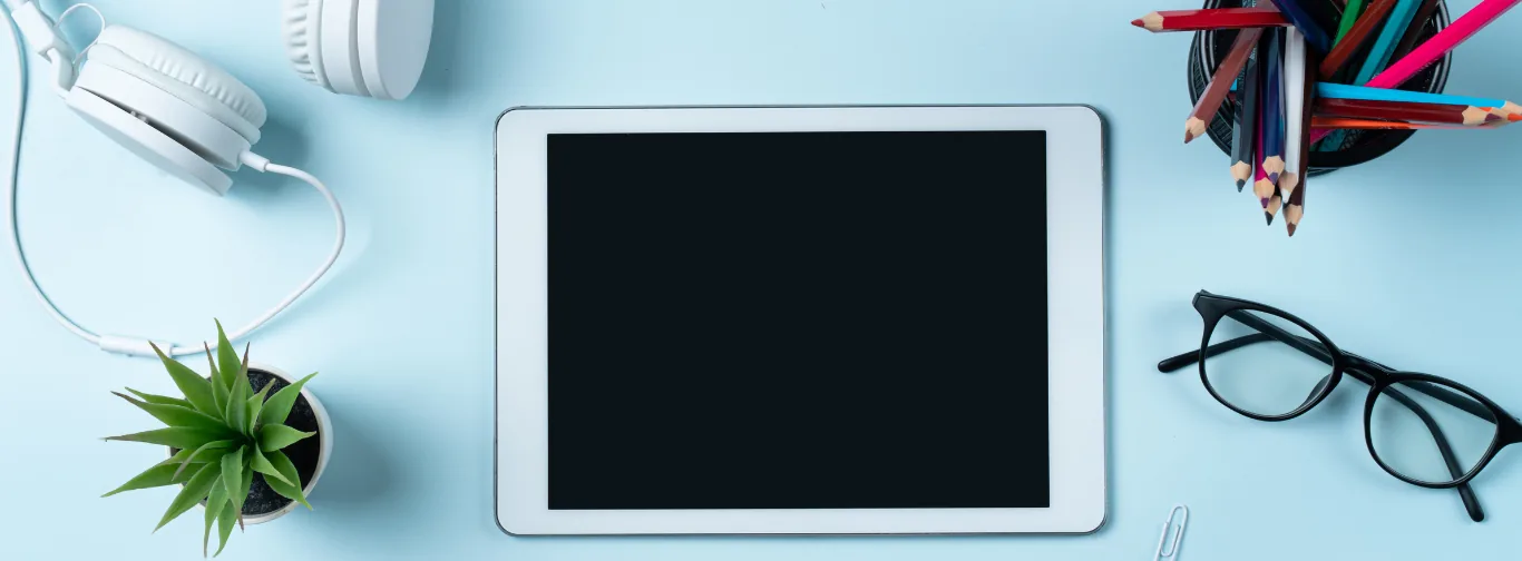 Tablet, fejhallgató, szemüveg és ceruzák világoskék asztalon – online tanulás