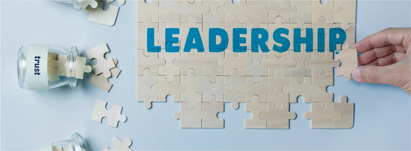 Fa kirakós elemek LEADERSHIP felirattal és egy puzzle-darabot tartó kézzel
